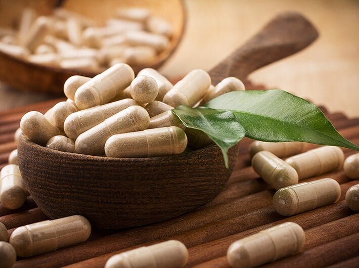 Botanical & Food Supplements - Tablets in a deep dish made from natural materials.